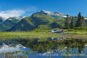 Float plane, water lilies and pond lie beneath the Chigmit Range near Silver Salmon Creek, Lake Clark National Park, Alaska