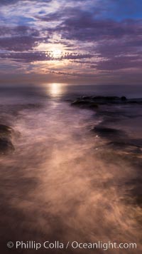 Breaking waves crash upon a rocky reef under the light of a full moon, La Jolla, California