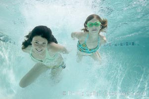 Two girls swimming through a cloud of bubbles in a swimming pool