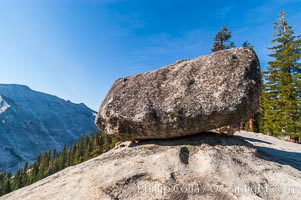 A glacial erratic hangs precariously at the precipice to Tenaya Canyon, with Clouds Rest in the background. Erratics are huge boulders left behind by the passing of glaciers which carved the granite surroundings into their present-day form, Yosemite National Park, California
