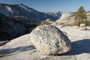 Glacial erratic boulder atop Olmsted Point, with the massive granite monoliths Half Dome and Clouds Rest in the background. Erratics are huge boulders left behind by the passing of glaciers which carved the granite surroundings into their present-day form.  When the glaciers melt, any boulders and other geologic material that it was carrying are left in place, sometimes many miles from their original location, Yosemite National Park, California