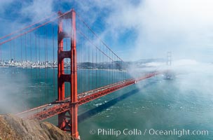 San Franciscos infamous summer fog overtakes the Golden Gate Bridge, viewed from the Marin Headlands with the city of San Francisco visible in the distance