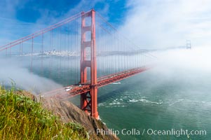 San Franciscos infamous summer fog overtakes the Golden Gate Bridge, viewed from the Marin Headlands with the city of San Francisco visible in the distance