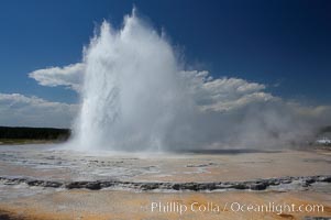 Great Fountain Geyser erupting.  Great Fountain Geyser, a fountain-type geyser, can reach heights of 200 feet, one of the largest geysers in the world.  It has a large vent (16 feet across) situated amid wide sinter terraces that act as reflecting pools as the geyser slows fills prior to its eruption.  Its interval and duration vary widely.  It typically erupts in a series of bursts, each separately by a few minutes.  Firehole Lake Drive, Lower Geyser Basin, Yellowstone National Park, Wyoming