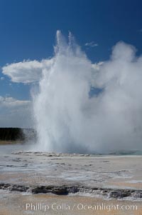 Great Fountain Geyser erupting.  Great Fountain Geyser, a fountain-type geyser, can reach heights of 200 feet, one of the largest geysers in the world.  It has a large vent (16 feet across) situated amid wide sinter terraces that act as reflecting pools as the geyser slows fills prior to its eruption.  Its interval and duration vary widely.  It typically erupts in a series of bursts, each separately by a few minutes.  Firehole Lake Drive, Lower Geyser Basin, Yellowstone National Park, Wyoming