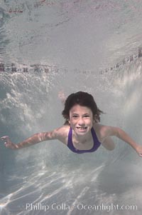 Having just leapt into a pool, this smiling kid emerges from a cloud of bubbles and smiles for the camera