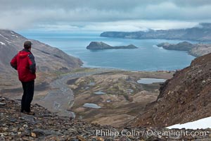 Hiker looks down on Stromness Harbour from the pass high above