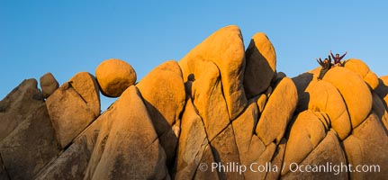 Hikers atop Jumbo Rocks at sunset, warm last light falling on the boulders