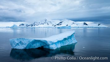 Iceberg and mountain panorama, cloudy morning.