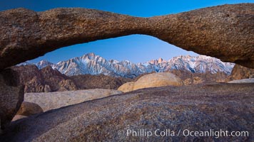 Mount Whitney and Lone Pine Peak are framed by Lathe Arch in the Alabama Hills at sunrise, California.