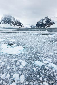 Lemaire Channel: mountains, sea, ice and clouds,Antarctica.  The Lemaire Channel, one of the most scenic places on the Antarctic Peninsula, is a straight 11 km long and only 1.6 km wide at its narrowest point