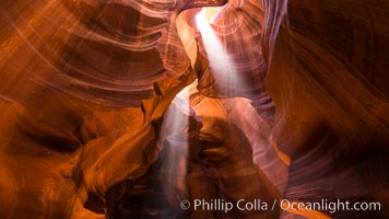 Light Beam in Upper Antelope Slot Canyon.  Thin shafts of light briefly penetrate the convoluted narrows of Upper Antelope Slot Canyon, sending piercing beams through the sandstone maze to the sand floor below, Navajo Tribal Lands, Page, Arizona