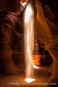 Light Beam in Upper Antelope Slot Canyon.  Thin shafts of light briefly penetrate the convoluted narrows of Upper Antelope Slot Canyon, sending piercing beams through the sandstone maze to the sand floor below, Navajo Tribal Lands, Page, Arizona