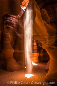 Light Beam in Upper Antelope Slot Canyon.  Thin shafts of light briefly penetrate the convoluted narrows of Upper Antelope Slot Canyon, sending piercing beams through the sandstone maze to the sand floor below, Navajo Tribal Lands, Page, Arizona