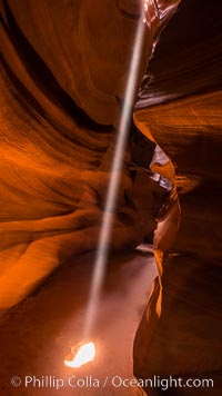 Light Beam in Upper Antelope Slot Canyon.  Thin shafts of light briefly penetrate the convoluted narrows of Upper Antelope Slot Canyon, sending piercing beams through the sandstone maze to the sand floor below, Navajo Tribal Lands, Page, Arizona