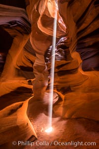 Image 28570, Light Beam in Upper Antelope Slot Canyon.  Thin shafts of light briefly penetrate the convoluted narrows of Upper Antelope Slot Canyon, sending piercing beams through the sandstone maze to the sand floor below. Navajo Tribal Lands, Page, Arizona, USA, Phillip Colla, all rights reserved worldwide. Keywords: adventure, antelope canyon, arizona, canyon, desert, environment, erosion, explore, geologic features, geology, gulch, landscape, narrow, nature, navaho, navajo tribal lands, outdoors, outside, page, ravine, sandstone, scene, scenery, scenic, slot, slot canyon, trail, tribal, upper antelope canyon, usa.