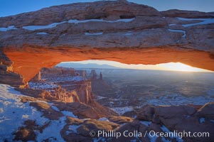 Mesa Arch spans 90 feet and stands at the edge of a mesa precipice thousands of feet above the Colorado River gorge. For a few moments at sunrise the underside of the arch glows dramatically red and orange, Island in the Sky, Canyonlands National Park, Utah