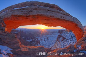 Mesa Arch spans 90 feet and stands at the edge of a mesa precipice thousands of feet above the Colorado River gorge. For a few moments at sunrise the underside of the arch glows dramatically red and orange, Island in the Sky, Canyonlands National Park, Utah