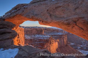 Mesa Arch spans 90 feet and stands at the edge of a mesa precipice thousands of feet above the Colorado River gorge. For a few moments at sunrise the underside of the arch glows dramatically red and orange, Island in the Sky, Canyonlands National Park, Utah