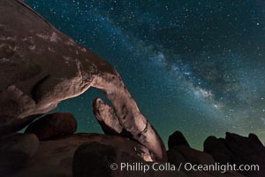 The Milky Way galaxy arcs over Arch Rock on a clear evening in Joshua Tree National Park