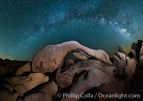 The Milky Way galaxy arches over Arch Rock on a clear evening in Joshua Tree National Park.