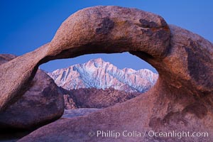 Snow-covered Lone Pine Peak framed within Moebius Arch, dawn.