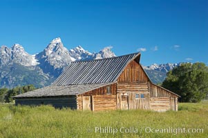 An old barn at Mormon Row is lit by the morning sun with the Teton Range rising in the distance, Grand Teton National Park, Wyoming
