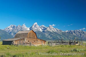 An old barn at Mormon Row is lit by the morning sun with the Teton Range rising in the distance, Grand Teton National Park, Wyoming