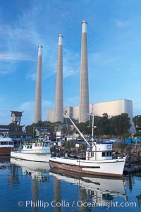 The Morro Bay Power Plant, with its distinctive three stacks, rises above fishing boats in Morro Bay harbor.  Morro Bay, California.
