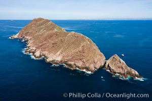 Aerial Photo of North Coronado Island, Baja California, Mexico, viewed from the southwest. The Keyhole, a spectacular narrow cut and underwater tunnel through the island, is seen at the narrow neck of the island. The San Diego and Tijuana coastline is visible in the distance, Coronado Islands (Islas Coronado)