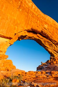 Hiker in North Window, sunset, western face.  North Window is a natural sandstone arch 90 feet wide and 48 feet high. Arches National Park, Utah.