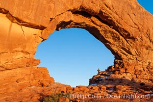 Hiker in North Window, sunset, western face.  North Window is a natural sandstone arch 90 feet wide and 48 feet high, Arches National Park, Utah