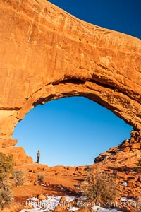 Hiker in North Window, sunset, western face.  North Window is a natural sandstone arch 90 feet wide and 48 feet high, Arches National Park, Utah