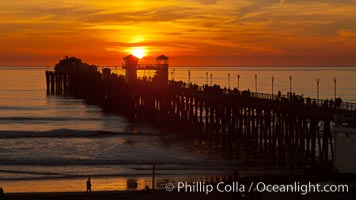 Oceanside Pier at sunset, clouds and palm trees with a brilliant sky at dusk