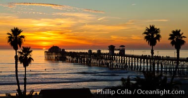 Oceanside Pier at sunset, clouds and palm trees with a brilliant sky at dusk
