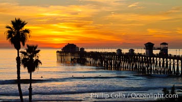 Oceanside Pier at sunset, clouds and palm trees with a brilliant sky at dusk