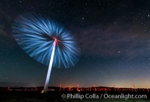 Stars rise above the Ocotillo Wind Turbine power generation facility, with a flashlight illuminating the turning turbine blades