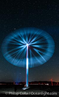 Stars rise above the Ocotillo Wind Turbine power generation facility, with a flashlight illuminating the turning turbine blades