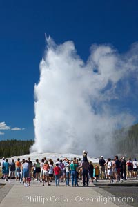 A crowd enjoys watching Old Faithful geyser at peak eruption.