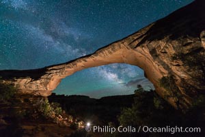 Owachomo Bridge and Milky Way.  Owachomo Bridge, a natural stone bridge standing 106' high and spanning 130' wide,stretches across a canyon with the Milky Way crossing the night sky.