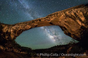 Owachomo Bridge and Milky Way.  Owachomo Bridge, a natural stone bridge standing 106' high and spanning 130' wide,stretches across a canyon with the Milky Way crossing the night sky.