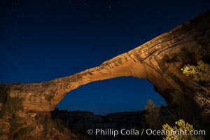 Owachomo Bridge at sunset, stars and blue sky.  Owachomo Bridge, a natural stone bridge standing 106' high and spanning 130' wide,stretches across a canyon with the Milky Way crossing the night sky, Natural Bridges National Monument, Utah