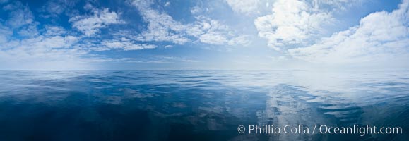 Ocean surface panorama, glassy calm ocean water offshore of California, clouds and sky.