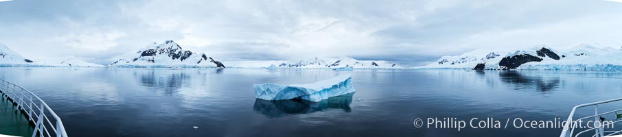 Iceberg and mountain panorama, cloudy morning.