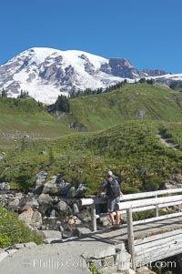 A hiker admires Mount Rainier from the footbridge crossing Edith Creek, Paradise Meadows, Mount Rainier National Park, Washington