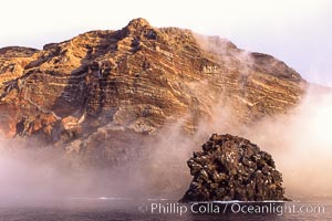 Pilot Rock (Roca Pilote), a undersea spire which extends 100 out of the water, stands below the immense seacliffs and morning clouds at the north end of Guadalupe Island (Isla Guadalupe), far offshore of the Baja California peninsula.