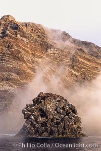 Pilot Rock (Roca Pilote), a undersea spire which extends 100 out of the water, stands below the immense seacliffs and morning clouds at the north end of Guadalupe Island (Isla Guadalupe), far offshore of the Baja California peninsula