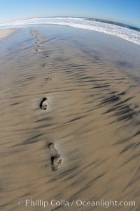 Empty beach after a session in the water, footprints in the sand.