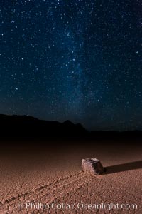 Racetrack sailing stone and Milky Way, at night. A sliding rock of the Racetrack Playa. The sliding rocks, or sailing stones, move across the mud flats of the Racetrack Playa, leaving trails behind in the mud. The explanation for their movement is not known with certainty, but many believe wind pushes the rocks over wet and perhaps icy mud in winter, Death Valley National Park, California