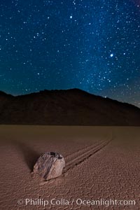 Racetrack sailing stone and Milky Way, at night. A sliding rock of the Racetrack Playa. The sliding rocks, or sailing stones, move across the mud flats of the Racetrack Playa, leaving trails behind in the mud. The explanation for their movement is not known with certainty, but many believe wind pushes the rocks over wet and perhaps icy mud in winter, Death Valley National Park, California